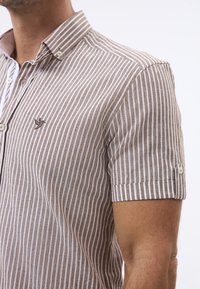 Kurzarmhemd mit einem braun-weißen gestreiften Muster, einem button-down Kragen und einem gestickten Logo auf der Brusttasche.
