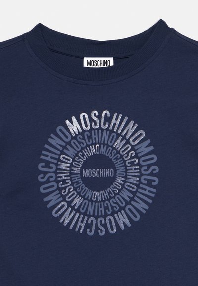 Temno modra majica z okroglim napisom "MOSCHINO" različnih velikosti in odtenkov, ki je nameščen osrednje pod rebrastim okroglim izrezom.