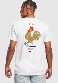 Hvid bomulds t-shirt med et farverigt hane grafik, to stjerner ovenfor og en fodbolde, med teksten "Équipe Tricolore" nedenfor.