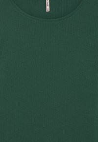 Mörkgrön ribbad tyg med rund halsringning och en klädlapp på baksidan av kragen som visar storlek 7-8Y 122-128.