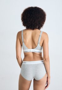 Sivi pamučni bralette s podesivim trakama i elastičnom trakom s logotipom, uparen s odgovarajućim kratkim hlačama koje imaju elastičnu traku s logotipom. Glatka tekstura, jednostavan dizajn.