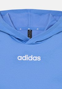 Kék kapucnis pulóver, puha anyagból készült. A mellkasán fehér "adidas" logó található, és a kapucni belsejében három kis fehér háromszög forma díszíti.