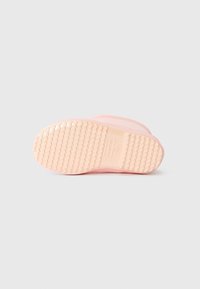 Botte en caoutchouc rose avec une semelle extérieure texturée, présentant des rainures horizontales et une finition lisse. Branding subtil visible sur la semelle.
