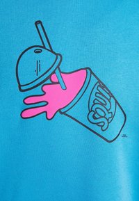 Turkos tyg har en grafisk design av en rosa slushdrink i en kopp med ett sugrör, accentuerad av svarta linjer.