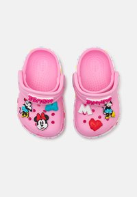 Roosa kummisaapad, millel on multika tegelaste lisandid, sealhulgas Minnie Mouse, ning värvilised punktid ääres. Ventilatsiooniavad on olemas.
