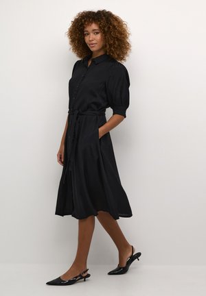 Zwart shirtjurk van soepel materiaal, met een knoopsluiting aan de voorkant, pofmouwen, een strikceintuur in de taille en een vloeiende rok.
