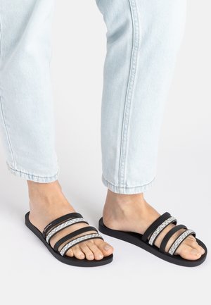 Black slide sandals with three wide straps, two adorned with silver accents, durable rubber sole, and minimalist design.