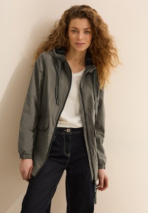 Lightweight, olive green hooded jacket with a zipper, elastic cuffs, and front pockets, paired with straight-leg dark denim jeans.