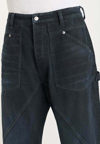 Donker denim broek met een gestructureerde afwerking, featuring schuine zakken, zilveren hardware en een klassieke vijfzakontwerp.