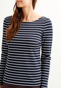 Randig långärmad topp i marinblått och vitt, tillverkad av mjukt tyg, med en vid halsringning och tajt passform.
