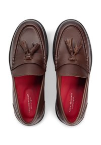 Καφέ δερμάτινα μοκασίνια με λείο φινίρισμα, διακοσμημένα με φούντες, μαύρες λαστιχένιες σόλες και κόκκινες εσωτερικές σόλες. Διακριτό ανάγλυφο λογότυπο.
