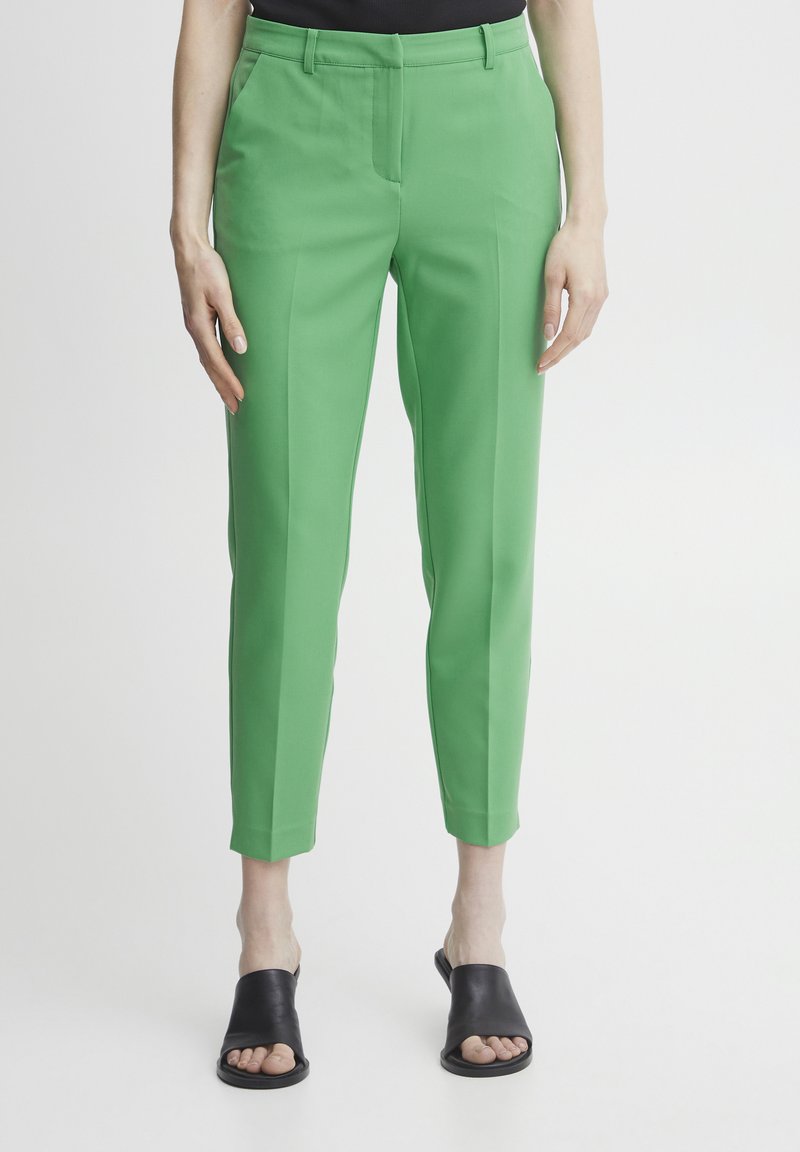 Zöld, slim fit szabású nadrág, sima textúrával, elülső zsebekkel és rövidített szegélyekkel, fekete slip-on szandállal párosítva.
