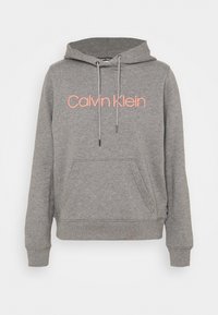 Felpa grigia con cappuccio e tasca frontale, con la scritta "Calvin Klein" in testo arancione brillante sul petto e regolazioni con cordino.