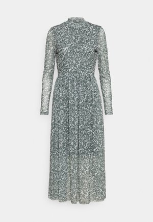 Longue robe verte transparente avec motif floral blanc, col montant, taille cintrée et manches longues.