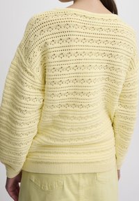 Suéter amarillo de punto que presenta un patrón texturizado de rayas horizontales y tejidos abiertos, con puños y dobladillo de canalé.