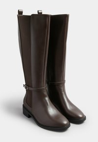 Brązowe kozaki do kolan, wykonane z gładkiej skóry, z elastycznymi panelami, paskiem z srebrną klamrą i niskim słupkowym obcasem. Płaska podeszwa.