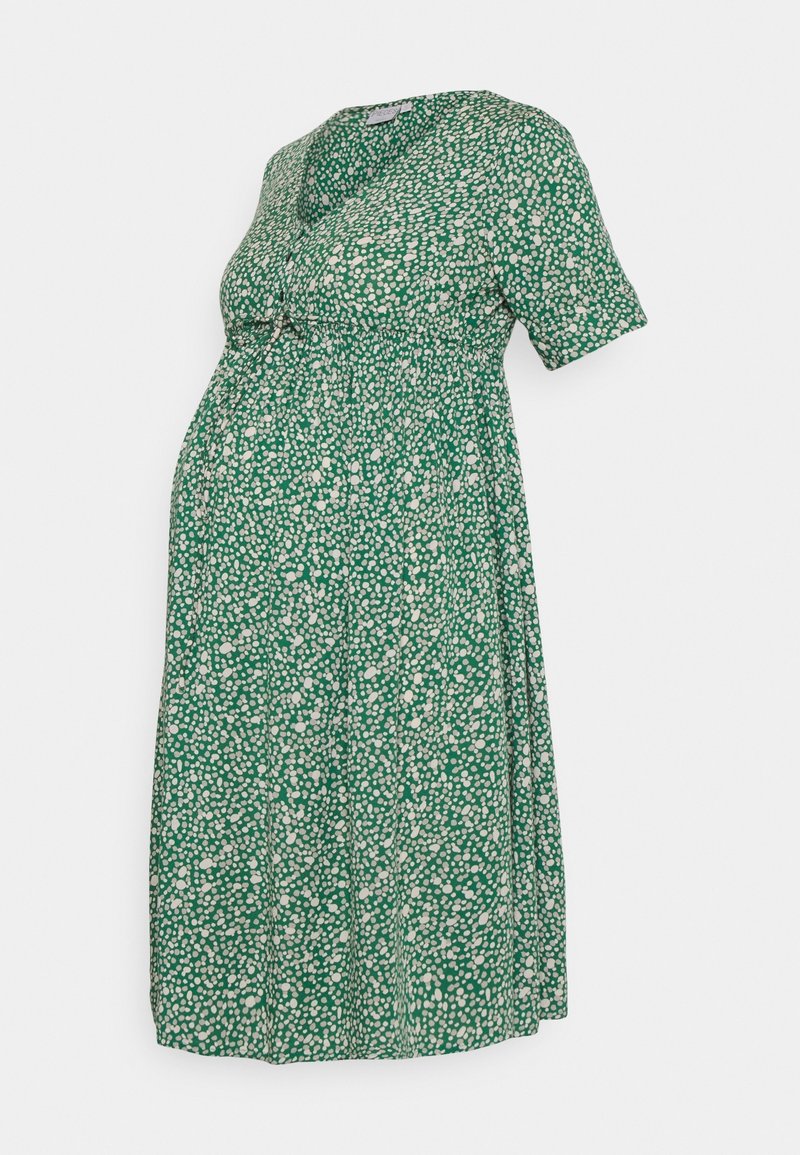 Abito premaman verde con maniche corte, scollatura con bottoni e vita aderente, caratterizzato da un motivo a macchie bianche su tutto l'abito.