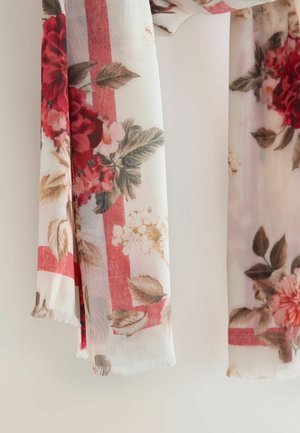 Kvetinová šatka z priehľadnej látky s červenými ružami, zelenými listami a svetlými pruhmi. Okraje sú olemované strapcami pre textúru.