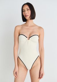 Utan axelremmar randig baddräkt i off-white med svarta detaljer, med ett nyckelhåls-ackcent och högskuren design, slät textur.