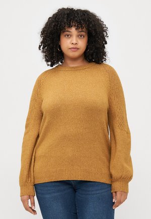 Senfgelber Pullover mit weichem Material, geripptem Saum und langen, leicht gepufften Ärmeln, die detaillierte Strickakzente an den Schultern haben.