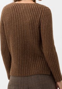 Pull en tricot marron avec une texture côtelée, un col bateau et des manches longues. Présente une coupe décontractée et un léger éclat.
