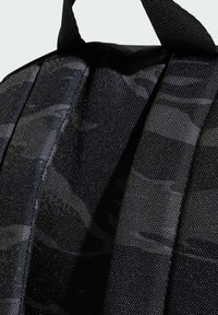 Mochila negra con tejido texturizado, que presenta correas acolchadas y costuras reforzadas. Enfoque en primer plano en los detalles del material y la construcción.