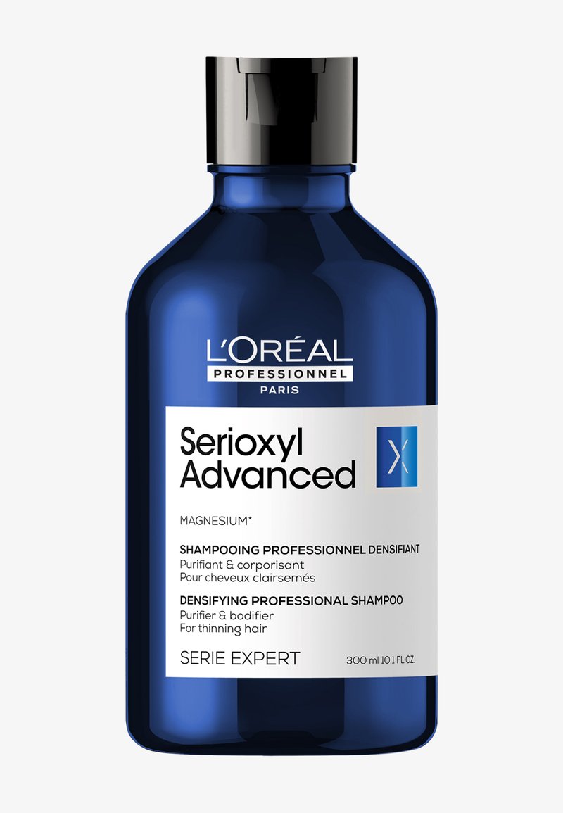 Champú L’Oréal Professionnel Serioxyl Advanced en una botella de vidrio azul con tapa negra. La etiqueta presenta texto en blanco y azul con detalles del producto.
