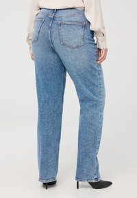 Jeans in denim azzurro chiaro con un design a gamba dritta, dotati di due tasche posteriori e di una cintura. La texture è liscia, con una leggera sfumatura.