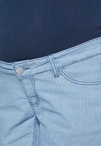 Denim riscado azul claro com corte reto, apresentando um fecho frontal com botão e zíper, costuras visíveis e um clássico design de 5 bolsos.