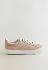 Baskets basses beige avec des lacets blancs et une semelle en caoutchouc blanche épaisse, vues de profil sur un fond clair.