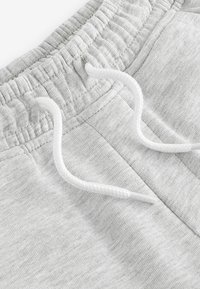 Lichtgrijze sweatpants met een geribde tailleband, witte trekkoorden en een zachte, gestructureerde stof met een subtiel patroon.