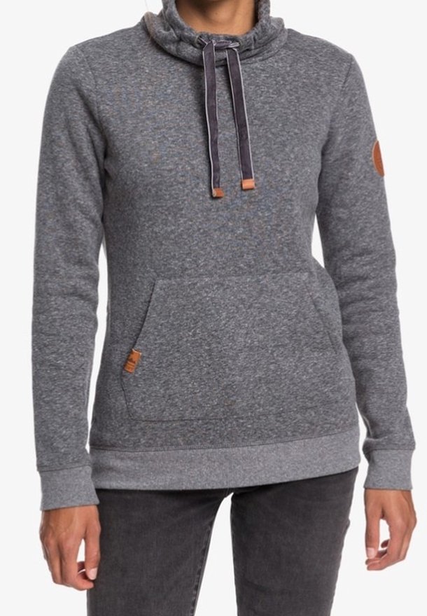 Personne portant un pull gris à manches longues avec une pochette kangourou et des cordons au col montant.