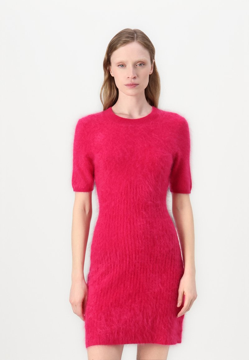 Fuchsia gestricktes Kleid mit kurzen Ärmeln, das eine weiche, strukturierte Oberfläche und eine taillierte Silhouette hat, die bis zur Mitte des Oberschenkels reicht.