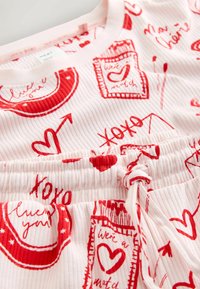 Set de pijamale din material roz cu nervuri, având imprimeuri cu inimi roșii și fraze, cu talie elastică și detaliu cu șnur.
