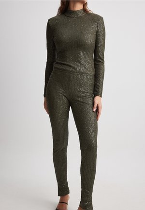 Olivgrünes, geripptes Strick-Outfit mit Pailletten, das einen hohen Kragen und lange Ärmel hat; tailliertes Oberteil und Hose mit glatter Textur.