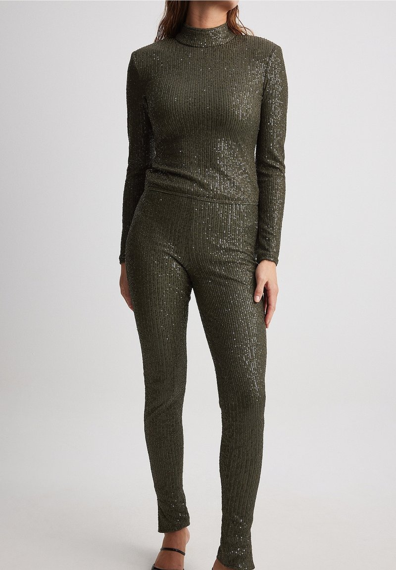 Ensemble tricot côtelé olive avec sequins, comportant un col haut et des manches longues ; haut et pantalon ajustés, avec une texture lisse.