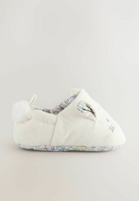 Zapatillas para niños hechas de un suave tejido blanco, con un forro de estampado floral, detalles de orejas de conejo y un pompón en la parte trasera.