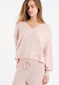 Felpa rosa chiaro in tessuto morbido con scollo a V, spalle scese, vestibilità ampia e design corto, abbinata a pantaloni con coulisse coordinati.