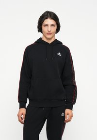 Sudadera con capucha negra con rayas laterales rojas y logo. Presenta un bolsillo frontal, cordones y puños acanalados en las mangas y el dobladillo.
