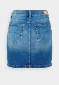 Džínová mini sukně v středně modré barvě, s kapsami vzadu, mírným efektem vyblednutí a lemem, který končí nad koleny.