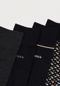 Μαύρες και σκούρες γκρίζες κάλτσες με ραβδωτή υφή, μία με σχέδιο από λευκά και χρυσά διαμάντια, με σήμανση στα μανίκια.