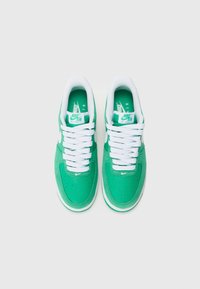 Green Nike Air Force 1 sneakers with white laces, featuring a smooth upper, perforated toe, and logo accents on the tongue and side.