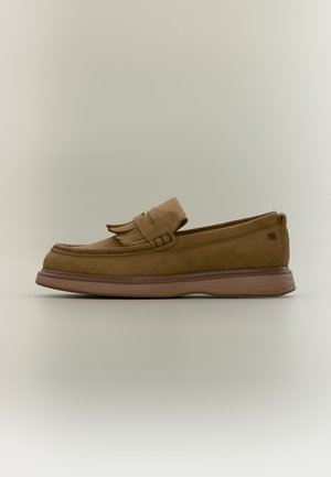 Brown leather loafer with fringe detail on top and a thick rubber sole on a plain light background.