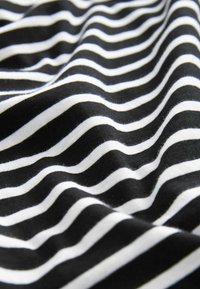 Tkanina w czarno-białe paski o gładkiej fakturze, z naprzemiennie grubymi i cienkimi paskami tworzącymi falisty wzór.