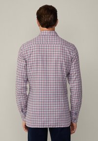 Camicia a scacchi con un motivo bianco, rosso e blu. Maniche lunghe, colletto con bottoni e una texture di cotone morbida. Vista posteriore mostrata.