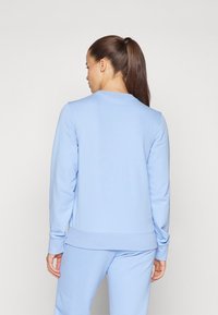 Sudadera azul claro con cuello redondo, mangas largas y puños y dobladillo acanalados. El material parece suave con una textura lisa.