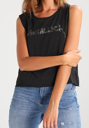 Top negro sin mangas con un gráfico desvanecido de "Metallica". Material de algodón suave, corte relajado y dobladillo ligeramente desgastado. Combinado con jeans azules.