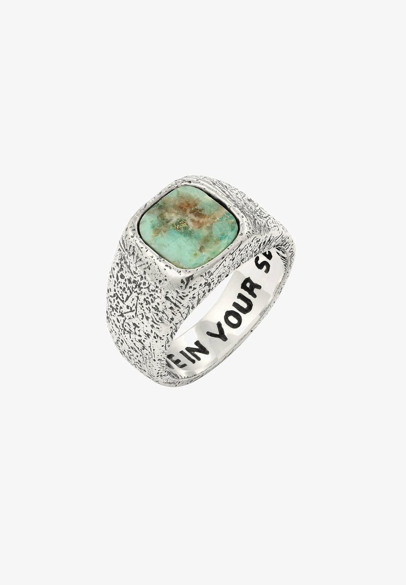 Hõbedane tekstuuriga sõrmus, mille ülaosas on ristkülikukujuline türkiisiklont; seespool on graveeritud julgete tähtedega "OLE OMA".