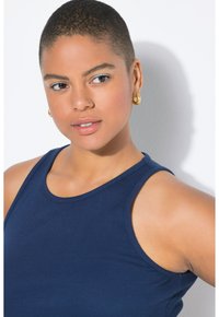 Top in tessuto a costine di colore blu navy, con scollatura rotonda, spalline larghe e vestibilità aderente. Orecchini a cerchio dorati completano il look.