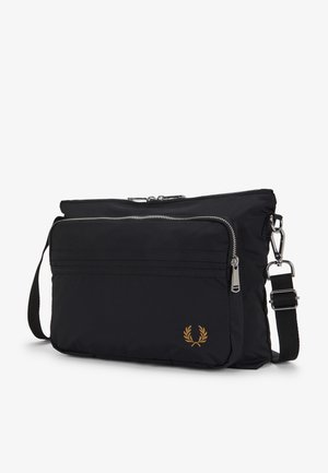 Sac bandoulière noir avec poche zippée à l'avant, bandoulière réglable et petit logo de couronne de laurier dorée en bas à droite.